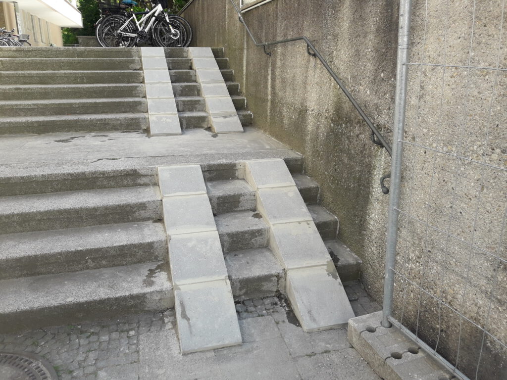 Fahrradrampe aus Betonelementen an einer bestehenden Treppenanlage im Außenbereich.